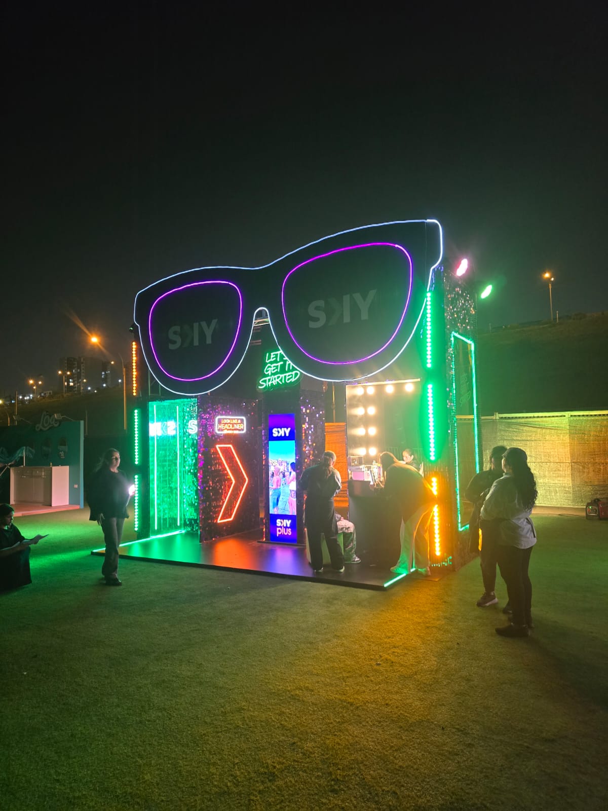 Vista frontal nocturna del stand SKY Plus